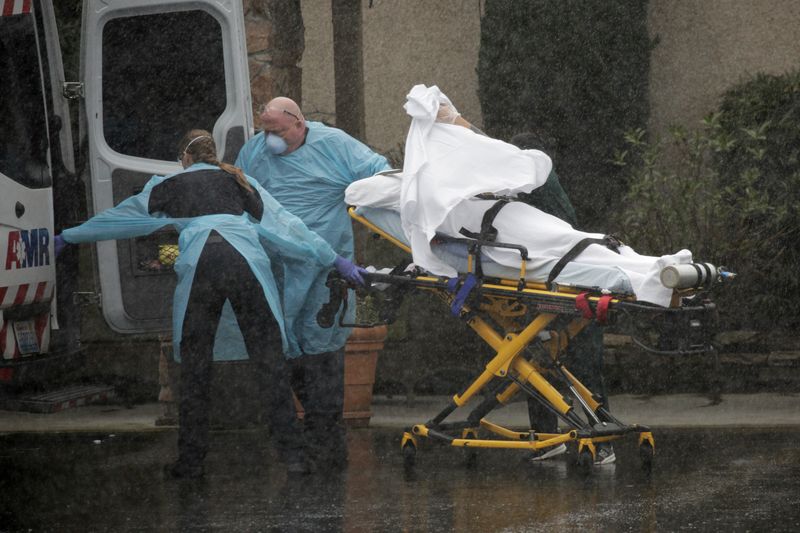 © Reuters. Medics transport a patient through heavy rain into an ambulance at Life Care Center of Kirkland