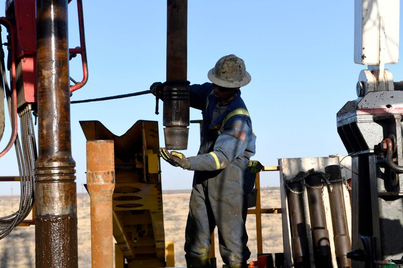 © Reuters. FILE PHOTO: An oil worker removes a thread cap from a piece of drill pipe near Midland, Texas