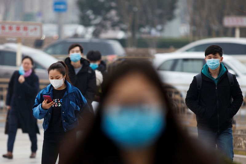 © Reuters. People wear face masks as they walk outside an office building during morning rush hour in Beijing as the country is hit by an outbreak of the novel coronavirus