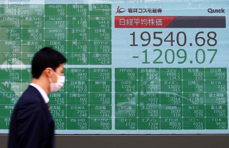 © Reuters. A passerby wearing a protective face mask walks past an electronic display outside a brokerage in Tokyo