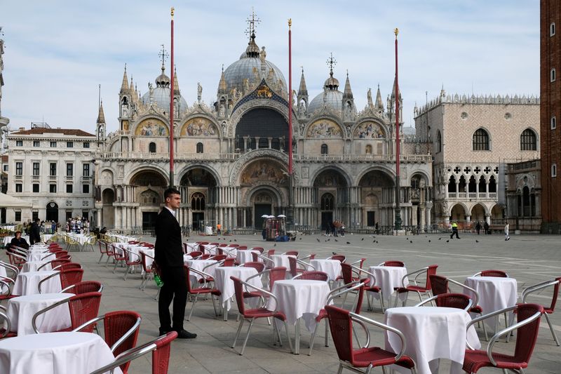 © Reuters. Un camarero de pie junto a mesas vacías frente a un restaurante en la Plaza de San Marcos de Venecia después de que el gobierno italiano impuso, en la práctica, un bloqueo en el norte de Italia, incluida Venecia, para tratar de contener un brote de cor