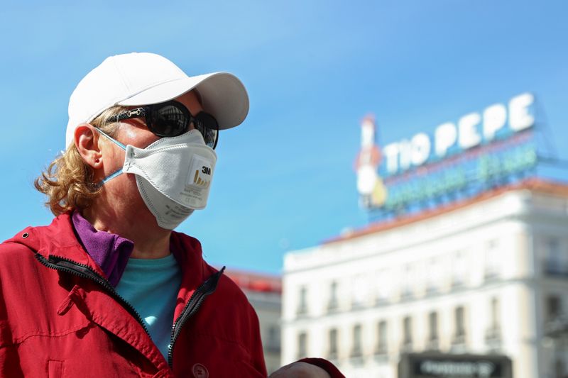 © Reuters. Una mujer con mascarilla, de pie en la Puerta del Sol en Madrid
