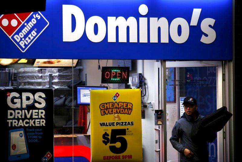 © Reuters. FILE PHOTO: A worker carries a pizza for delivery as he exits a Domino's pizza store in Sydney, Australia