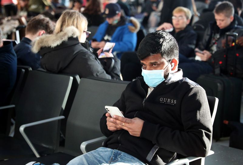 © Reuters. A man wears a surgical mask as he sits in Terminal 5 at Heathrow Airport in London