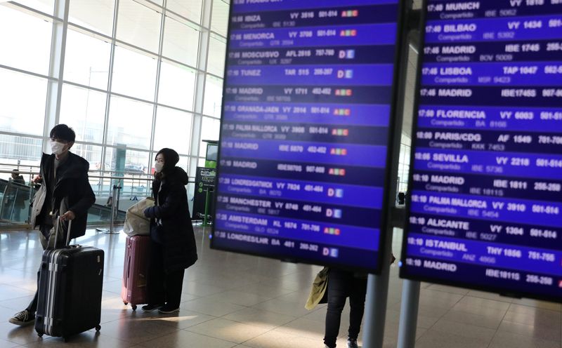 © Reuters. Turisti con maschere protettive all'aeroporto Josep Tarradellas Barcelona-El Prat