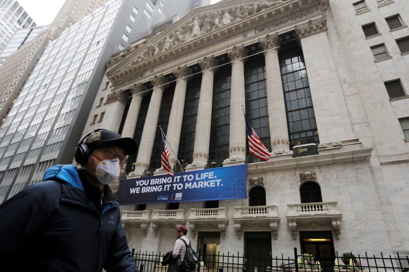 © Reuters. A man in a surgical mask walks by the New York Stock Exchange (NYSE) after more cases of coronavirus were confirmed in New York City, New York