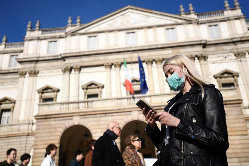© Reuters. Una mujer con una mascarilla mira su teléfono fuera del Teatro alla Scala, cerrado por las autoridades debido a un brote de coronavirus, en Milán