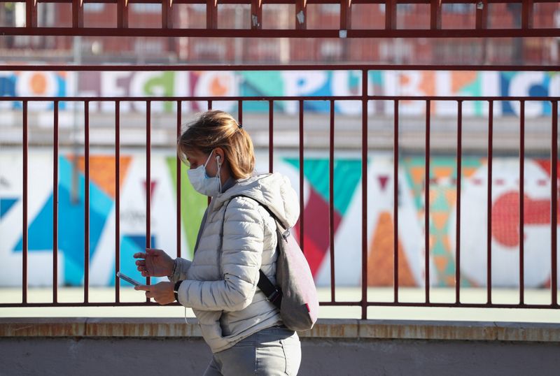 © Reuters. Una mujer con la cara cubierta con una máscara facial camina frente a una escuela cerrada como precaución contra el coronavirus en Madrid