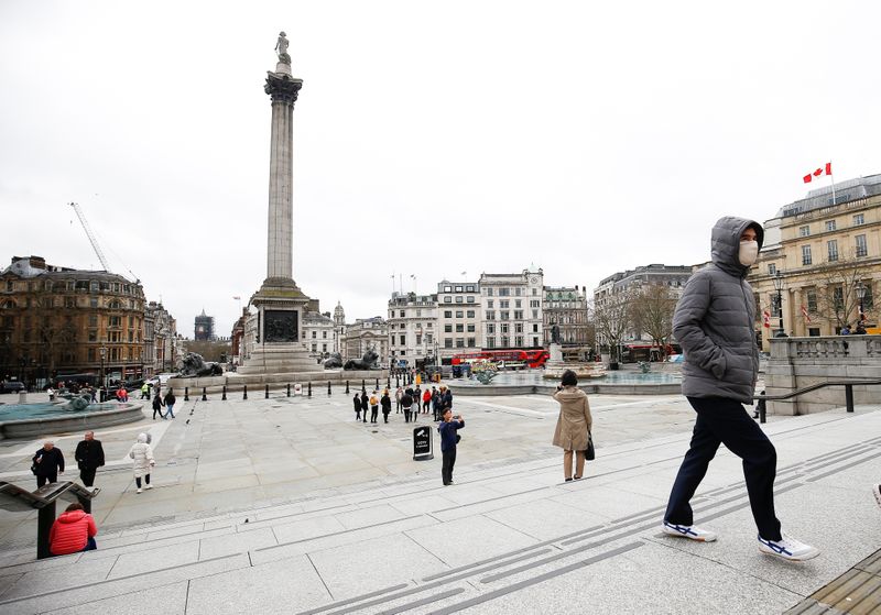 © Reuters. Homem caminha pela Trafalgar Square, em Londres, com máscara de proteção contra o coronavírus