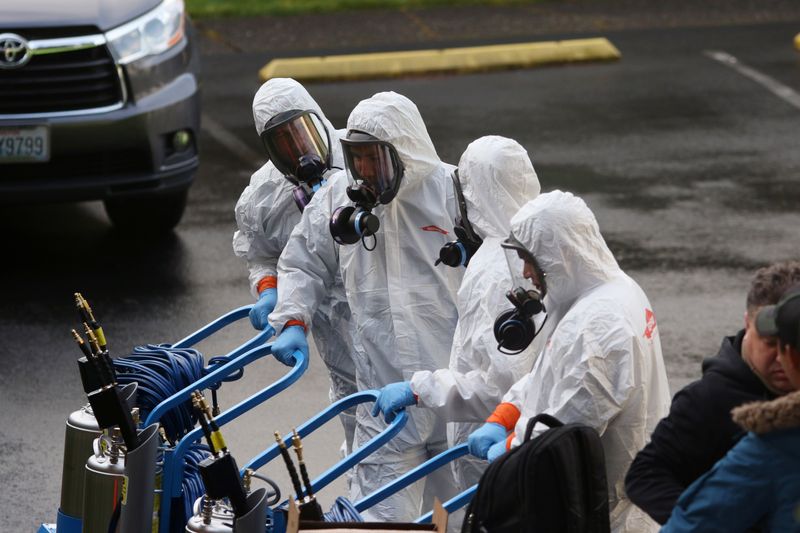 © Reuters. Los miembros de un equipo de limpieza de Servpro usan trajes de materiales peligrosos mientras se preparan para ingresar al Centro de Cuidado de Vida de Kirkland, el hogar de ancianos del área de Seattle en el epicentro de uno de los mayores brotes de coronavirus en los Estados Unidos, en Kirkland