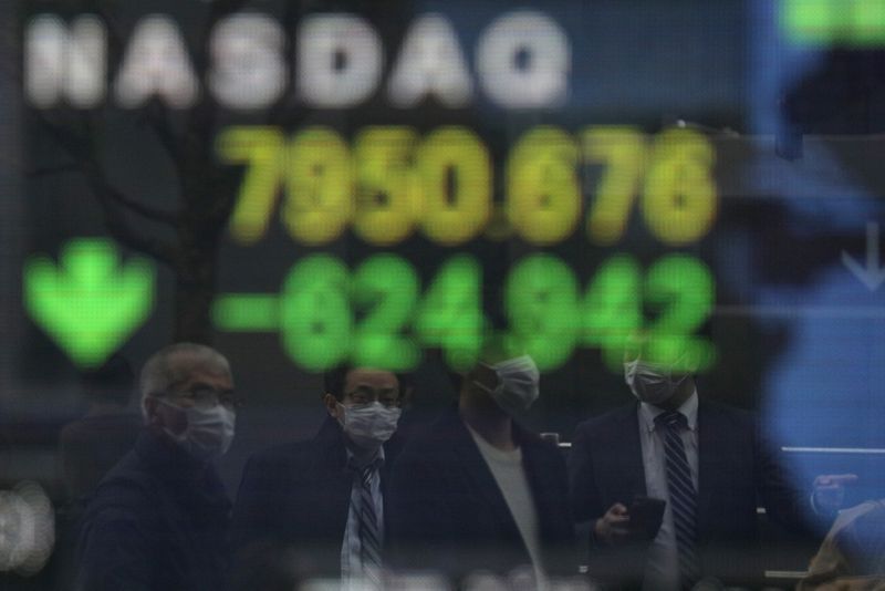 © Reuters. FILE PHOTO: People wearing protective face masks are reflected in a stock quotation board outside a brokerage in Tokyo