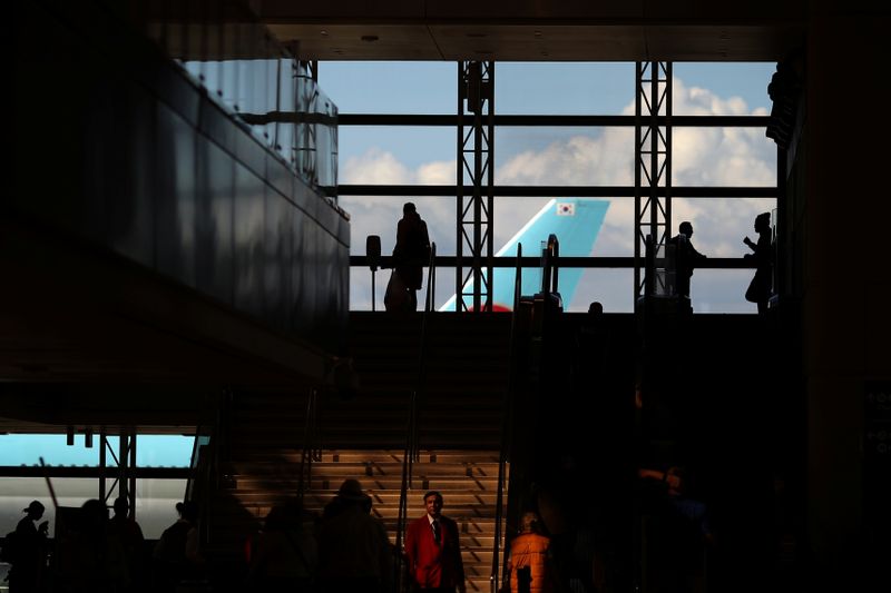 &copy; Reuters. People walk through the international terminal at LAX airport in front of a Korean Air plane in Los Angeles