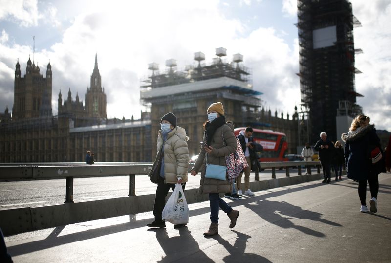 © Reuters. The Houses of Parliament can be seen as people wearing protective face masks walk across Westminster Bridge, as the number of coronavirus (COVID-19) cases around the world continues to grow, in London
