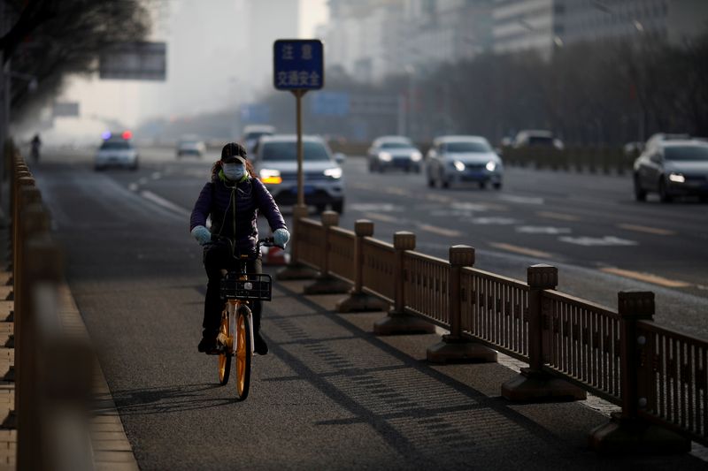 © Reuters. FILE PHOTO: Woman wearing a face mask rides a shared bicycle on a main road in central Beijing in the morning after the extended Lunar New Year holiday caused by the novel coronavirus outbreak