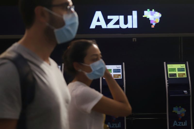© Reuters. Passageiros com máscaras de proteção caminham em frente a guichês da Azul no aeroporto de Congonhas, em São Paulo