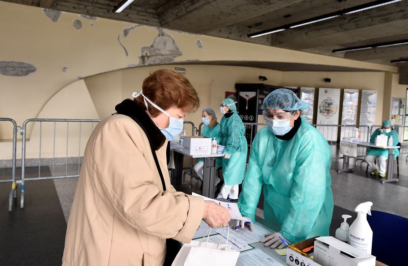 © Reuters. FILE PHOTO: Medical workers wearing protective masks check patients at a medical checkpoint at the entrance of the Spedali Civili hospital in Brescia