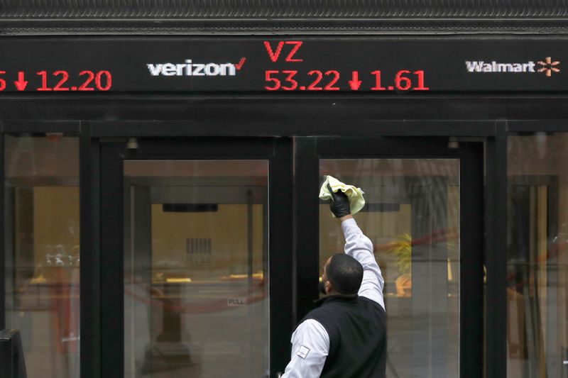 © Reuters. A worker wipes down an entrance to the New York Stock Exchange (NYSE) under trading information as more cases of coronavirus were confirmed in New York City