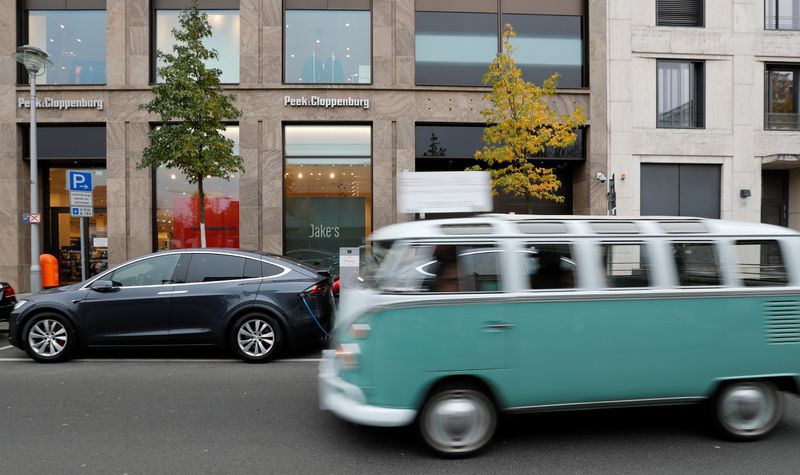 © Reuters. Volkswagen Kombi, modelo antigo de perua da montadora alemã, passa por veículo elétrico Tesla Model X recarregando em Berlim