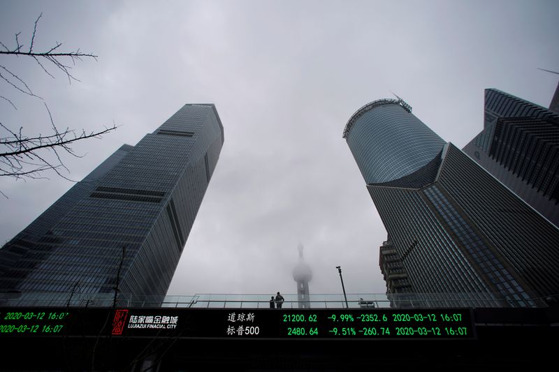 © Reuters. People are seen on a pedestrian overpass with an electronic board showing the Dow Jones and S&P 500 indexes, following an outbreak of the novel coronavirus in the country, at Lujiazui financial district in Shanghai