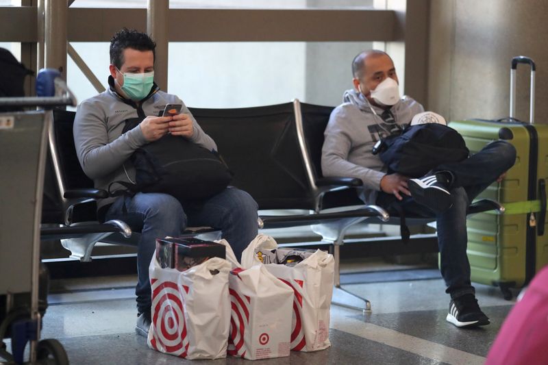 © Reuters. FILE PHOTO: People wear masks at the international terminal at LAX airport in Los Angeles