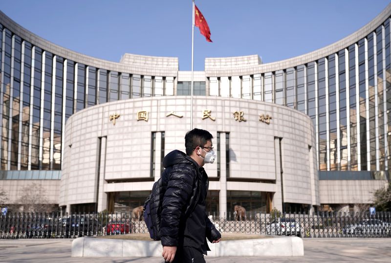 © Reuters. FOTO DE ARCHIVO: un hombre con una máscara pasa por la sede del Banco Popular de China, el banco central, en Beijing