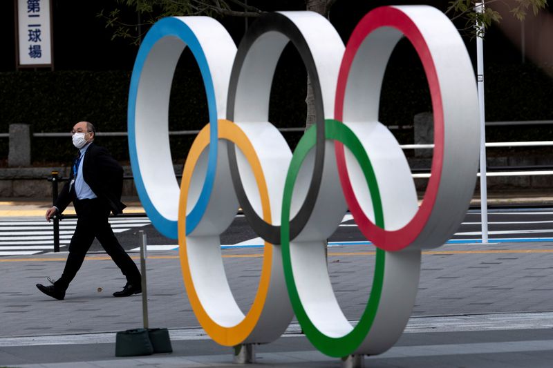 © Reuters. Un hombre que llevaba una máscara facial protectora, luego de un brote de la enfermedad por coronavirus (COVID-19), pasa junto a los anillos olímpicos frente al Museo Olímpico de Japón en Tokio.