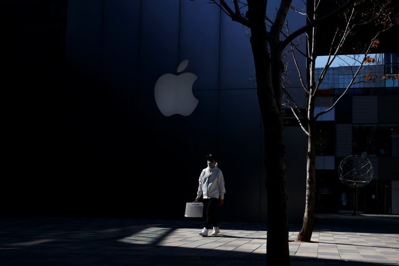 © Reuters. A man wearing a face mask walks past an Apple store in an upmarket shopping district in Beijing as the country is hit by an outbreak of the novel coronavirus