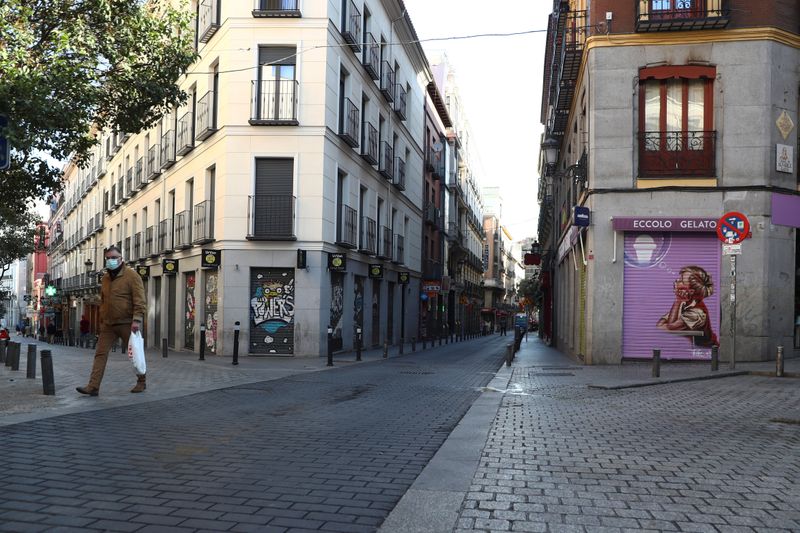 © Reuters. Man walks with his shopping bag through an empty street in Madrid