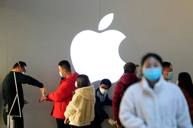 © Reuters. FOTO DE ARCHIVO. Personas que usan mascarillas protectoras esperan para controlar su temperatura en una tienda de Apple, en Shanghái, China, mientras el país se ve afectado por un brote del nuevo coronavirus.