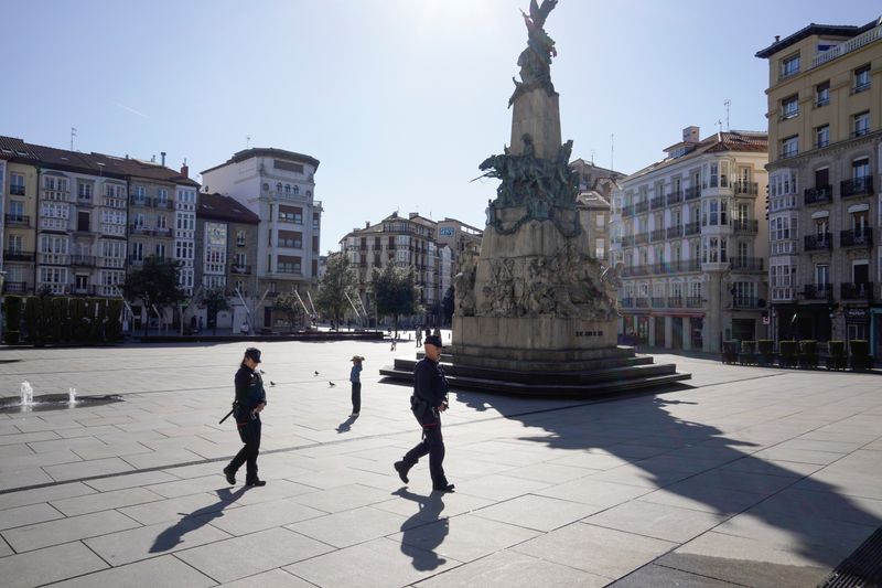 © Reuters. Police officers cross a virtually deserted square, amidst concerns over Spain's coronavirus outbreak, in the Basque city of Vitoria,