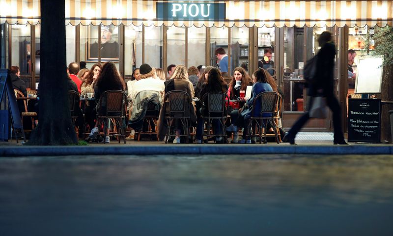 © Reuters. People sit in a outside restaurant, as France's Prime Minister announced to close most all non-indispensable locations, notably cafes, restaurants, cinemas, nightclubs and shops from midnight on Saturday, In Paris