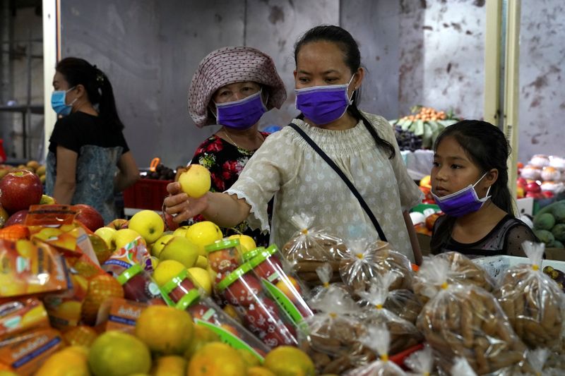© Reuters. Una familia utiliza máscaras protectoras mientras compra en un mercado de Phnom Penh