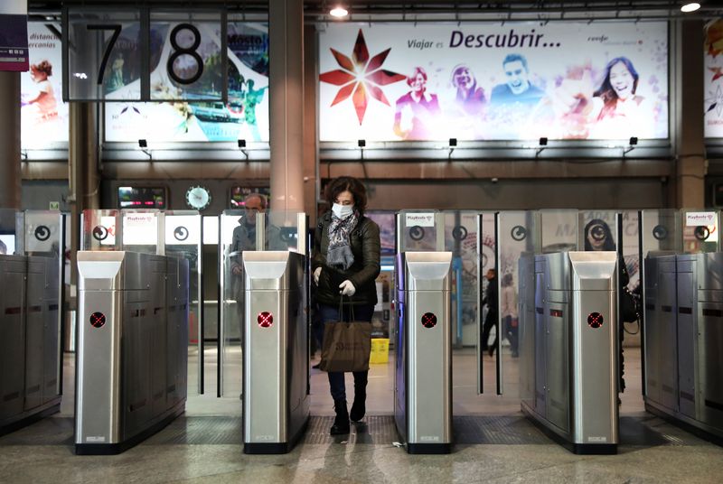 © Reuters. Una mujer con una mascarilla protectora camina por la estación de tren de Atocha casi vacía a la hora punta durante el estado de alarma de 15 días para combatir el brote de coronavirus en Madrid