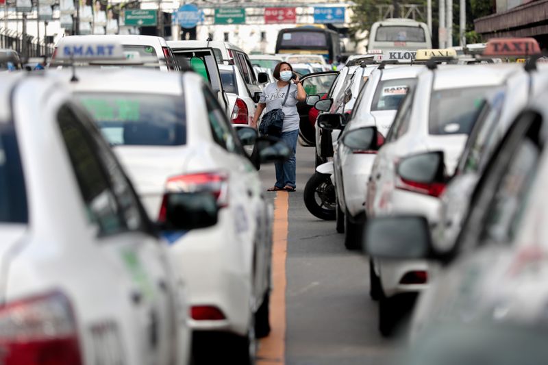 © Reuters. A pedestrian wearing a protective mask struggles to get a ride after hundreds of cabs were flagged down by authorities as the government suspends mass transportation to implement an "enhanced community quarantine" in the country’s main island 