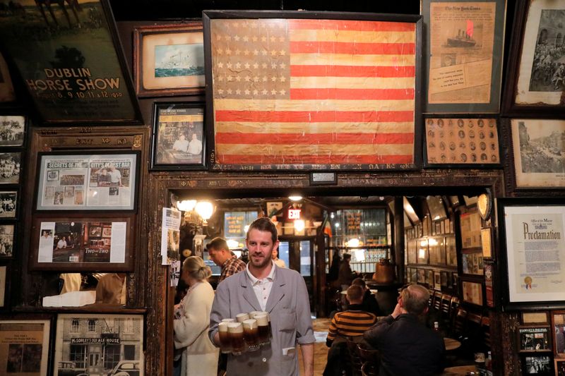 © Reuters. Server David Buggy carries a round of drinks to a table at McSorley's Old Ale House, which, established in 1854, is referred to as New York City's oldest Irish saloon and was ordered to close at 8:00pm as part of a city-wide order