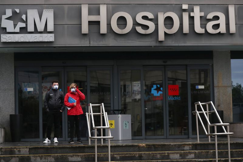 © Reuters. People wearing protective face masks walk outside a hospital during the partial lockdown as part of a 15-day state of emergency following the coronavirus disease outbreak in Madrid