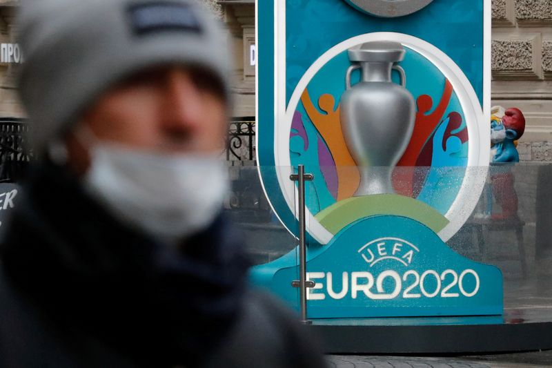 © Reuters. FILE PHOTO: A person wearing a protective face mask walks past the Euro 2020 countdown clock in Saint Petersburg