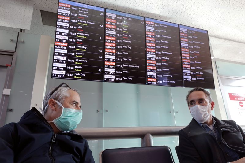 © Reuters. FILE PHOTO: Travellers wearing protective face masks wait for their flights at Nice International airport in Nice