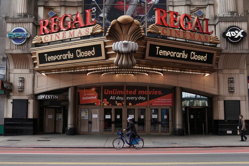 © Reuters. A man cycles past a shuttered movie theater in Manhattan's Times Square following the outbreak of coronavirus disease