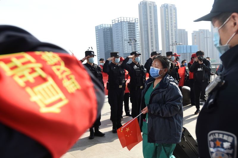 © Reuters. Police officers salute as a medical worker from outside Wuhan arrives at the Wuhan Railway Station before leaving the epicentre of the novel coronavirus disease outbreak