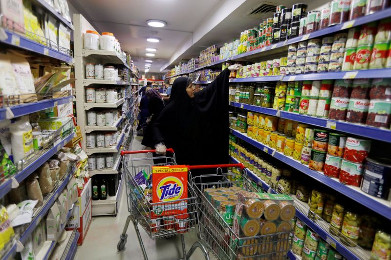 © Reuters. FILE PHOTO: A woman wears gloves, as she shops at a supermarket before curfew, following the outbreak of coronavirus, in Baghdad