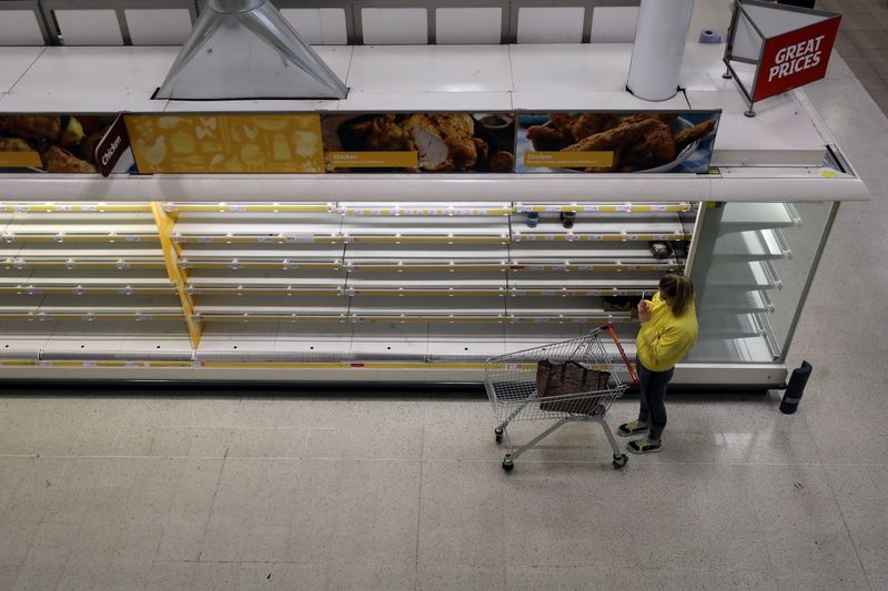 © Reuters. A woman takes a photo of empty shelves at Sainsbury's supermarket