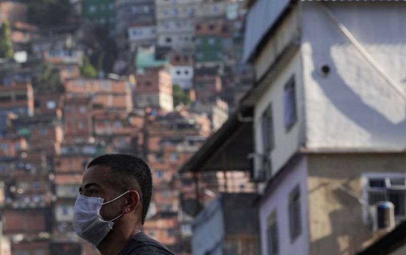 © Reuters. A man wearing a protective mask outside Rocinha Slum waits for a public bus during the coronavirus disease (COVID-19) outbreak in Rio de Janeiro