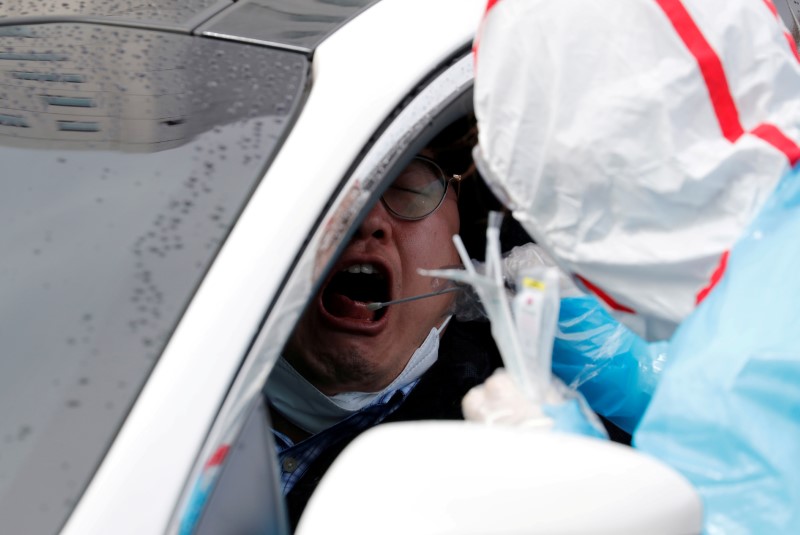 © Reuters. FILE PHOTO: A medical staff member in protective gear uses a swab to take samples from a visitor at 'drive-thru' testing center for the novel coronavirus disease of COVID-19 in Yeungnam University Medical Center in Daegu