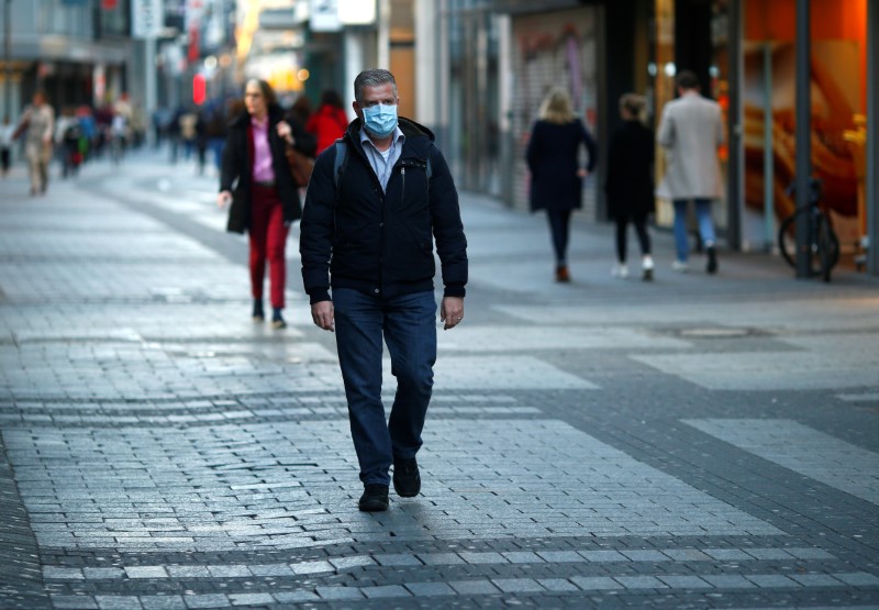 © Reuters. A man wearing a protective mask walks in the main shopping street as shops are closed during the spread of the coronavirus disease (COVID-19) in Cologne