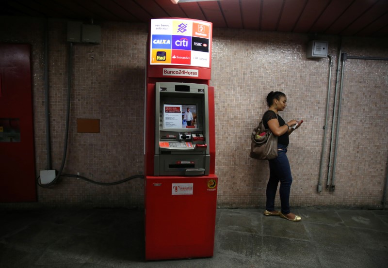 © Reuters. Mulher utiliza o celular ao lado de caixa eletrônico no Rio de Janeiro