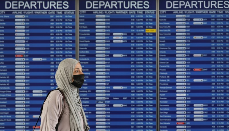 © Reuters. A woman passes a departure board at Dulles International Airport in Virginia