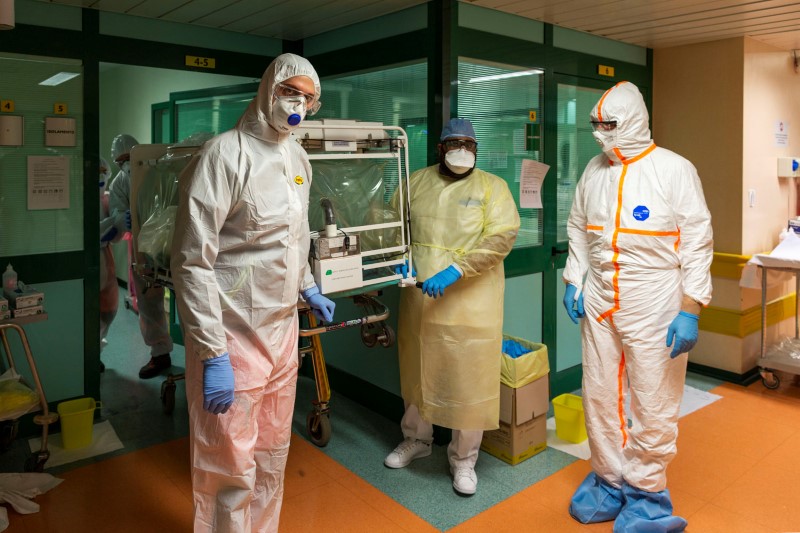 © Reuters. Funcionários de hospital em Roma, na Itália, utilizam roupas protetoras para transferir paciente com coronavírus para UTI