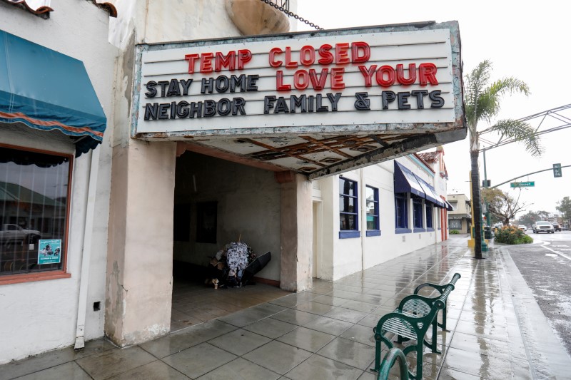 © Reuters. FILE PHOTO: A homeless person shelters from the rain under a movie theatre sign during the  global outbreak of the coronavirus disease (COVID-19)  in Encinitas, California