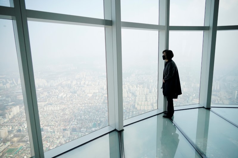 © Reuters. A woman wearing a mask to prevent contracting the coronavirus looks at a view of central Seoul